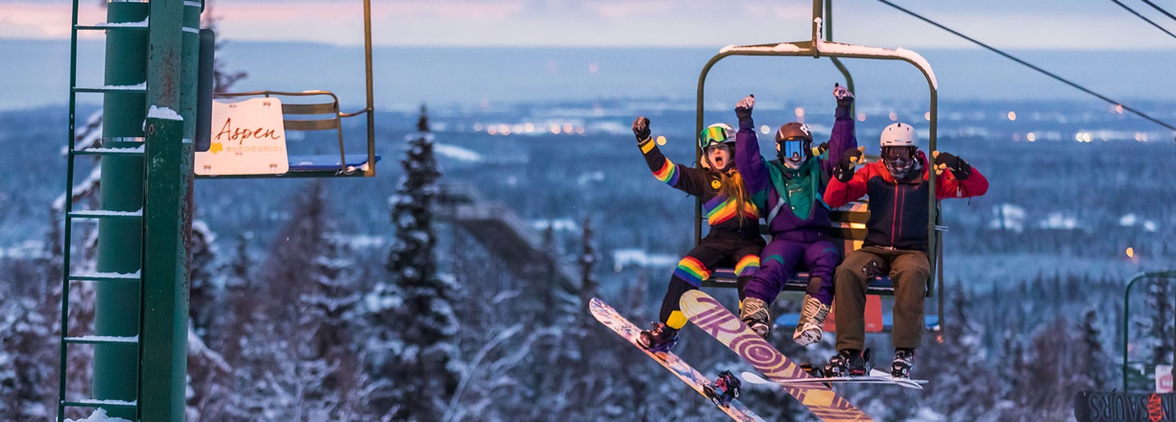 Three friends on the ski lift showing excitement