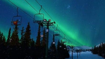 Ski lift at night with Northern Lights in the sky.